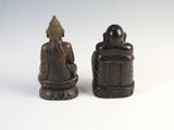 two figurines of a person sitting on a stool