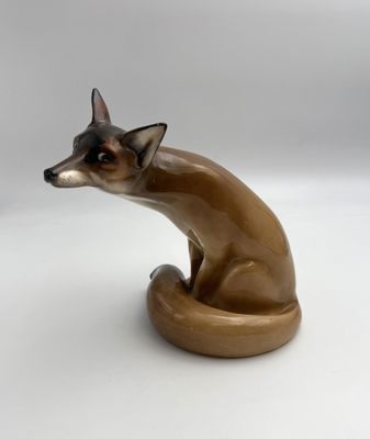 une figurine représentant un chat assis sur une surface blanche