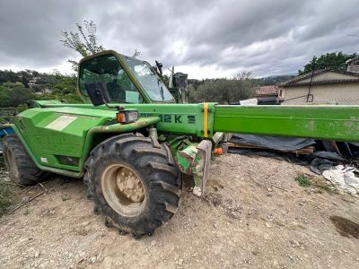 un tracteur vert garé sur la terre battue