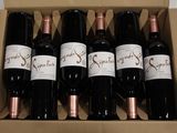 six bottles of wine in a cardboard box on a table