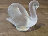 a glass swan that is sitting on a wooden table