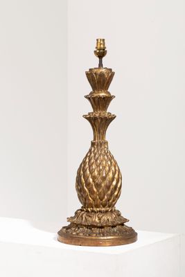lampe de table en forme d'ananas doré posée sur un socle blanc, sur fond blanc