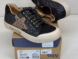 des baskets noires à imprimé léopard, avec des lacets, posées sur une boîte en carton