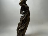 a bronze statue of a woman holding a pot