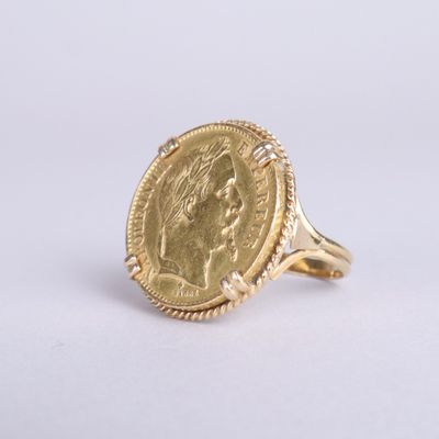 un gros plan d'une bague en or sur laquelle est gravé le visage d'une femme