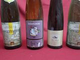four bottles of wine are lined up on a pink surface