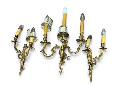three brass wall sconces with candles on each of them