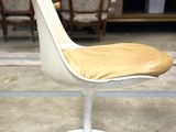 a white chair with a yellow seat on a white pedestal