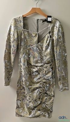 a silver dress hanging on a hanger against a wall