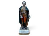 statue d'un homme vêtu d'un manteau et d'un chapeau, posée sur une surface blanche