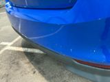 a close up of a blue car parked in a parking lot