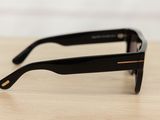 black sunglasses on a wooden table with a white wall in the background