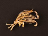 un gros plan d'une broche en or ornée de feuilles