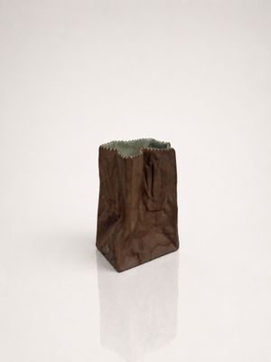 a brown paper bag with a handle sitting on a white surface