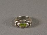 a close up of a ring with a peridot stone in it