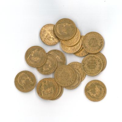 quelques pièces d'or sont éparpillées sur une surface blanche, sur fond blanc