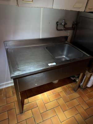 un évier dans un coin d'une cuisine au sol carrelé