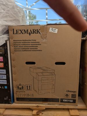 une personne montrant du doigt un carton contenant une imprimante, posé sur une palette