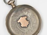a small silver pocket watch with a map on it