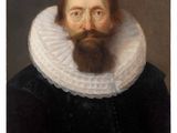 portrait of a bearded man in a black dress with a white ruffled collar