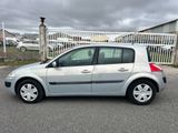 La voiture argentée est garée sur le parking, près d'une clôture.