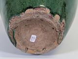 a green vase with a hole in the middle of it