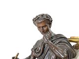 bronze statue of a man sitting on a marble pedestal with a book and pen