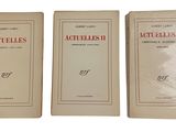 Trois livres sont posés sur une surface blanche ; l'un est rouge et l'autre est blanc.