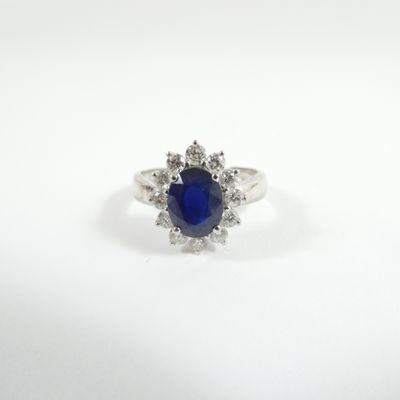 a close up of a blue sapphire and diamond ring on a white surface