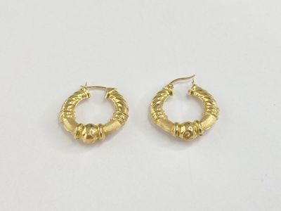 une paire de boucles d'oreilles en or sur fond blanc