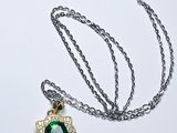 collier composé d'une pierre verte entourée d'une chaîne sur un fond blanc