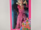 La poupée Barbie se trouve dans une boîte rose posée sur une surface blanche.