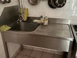 une cuisine équipée d'un évier, d'une cuisinière et de casseroles accrochées au mur