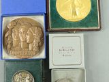 trois médailles d'argent et d'or dans des coffrets posés sur un fond blanc