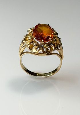 yellow gold ring with an orange topaz stone surrounded by leaves