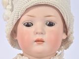 a doll that is wearing a white sweater and a hat
