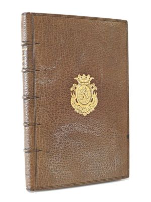 un livre en cuir marron orné d'un emblème doré sur la couverture
