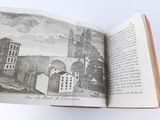 an open book with a picture of a city in it