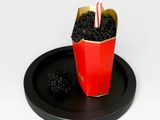 a red cup with blackberries in it on a black tray