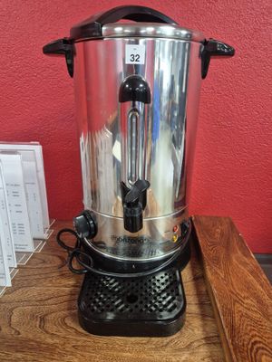 une cafetière posée sur une table en bois, avec un mur rouge en arrière-plan