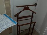 a coat rack with a coat hanger on it in the corner of a room