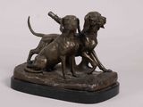 bronze statue of two dogs on a rock with a baseball bat in its mouth