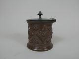 une image représentant un petit pot marron muni d'un couvercle, posé sur une surface blanche