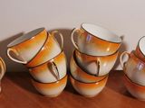 five cups and a pitcher sitting on a table next to each other