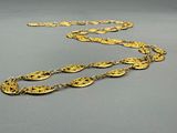 an image of a gold necklace with a long chain on a gray surface