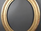 an oval gold frame with a decorative pattern on the rim