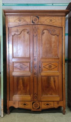a wooden armoire in a room with a green wall