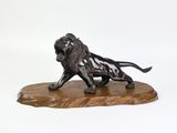 statue d'un lion posée sur un socle en bois, sur fond blanc