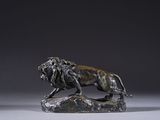 bronze statue of a lion on a rock on a grey background