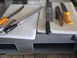 trois couteaux posés sur une planche à découper, elle-même posée sur une table